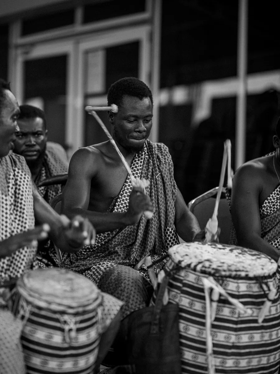 Bębniarz grający na tradycyjnych bębnach ręcznych w Akrze, Ghana, czarno-białe (reprezentatywne zdjęcie afrykańskiej gry na bębnach, nie własny zespół Safari Cats)